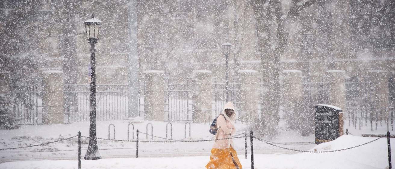 A student walks across campus in the snow