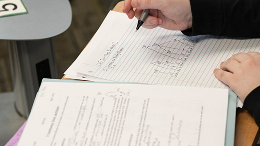 Closeup of UI student's hands taking notes in a notebook.